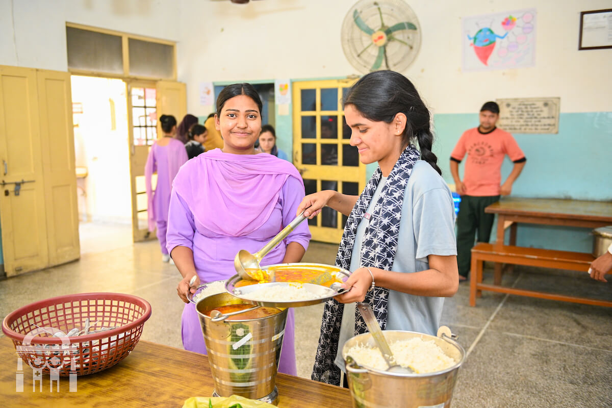 Nursing students at mess hall serving dinner and smiling - Guru Nanak Paramedical College Dhahan Kaleran